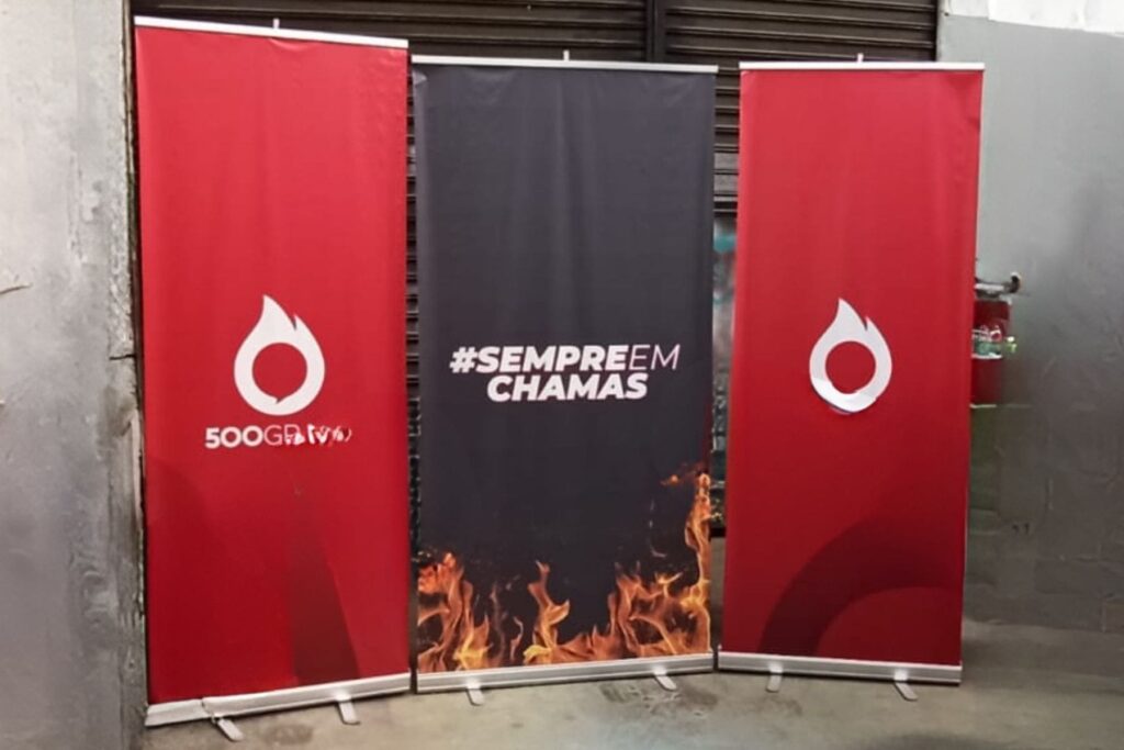 Três porta-banners roll-up impressos montados lado a lado na produção