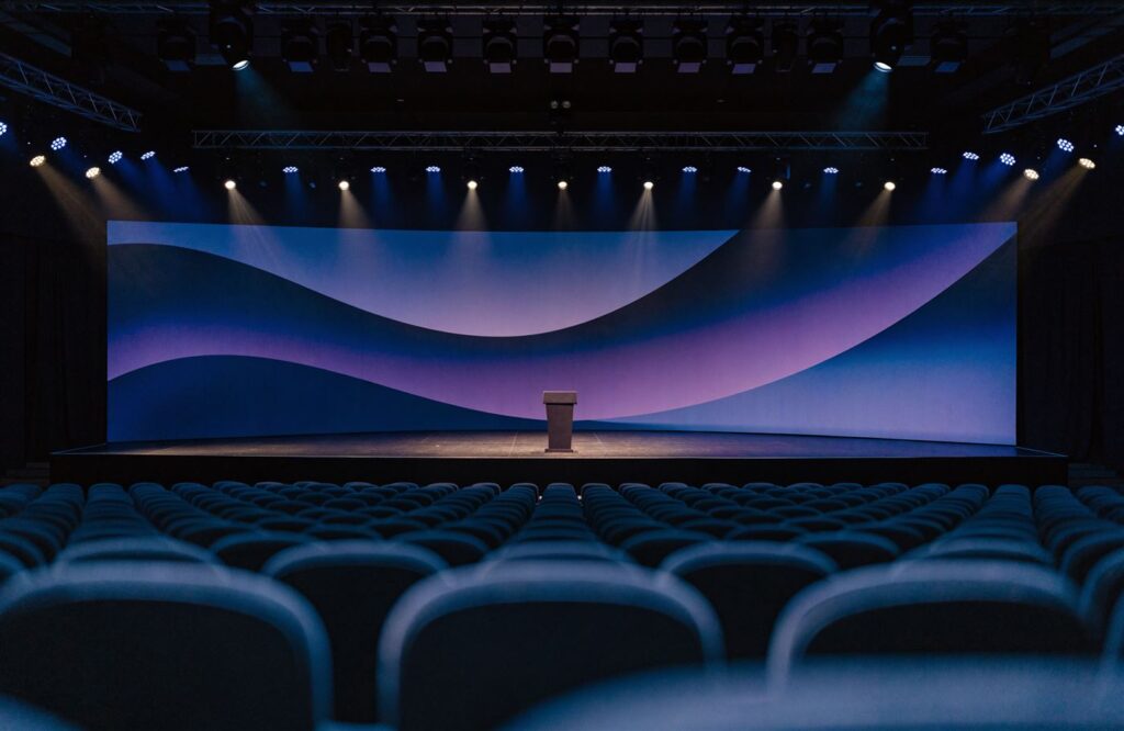 Auditório com painel impresso iluminado como fundo de palco