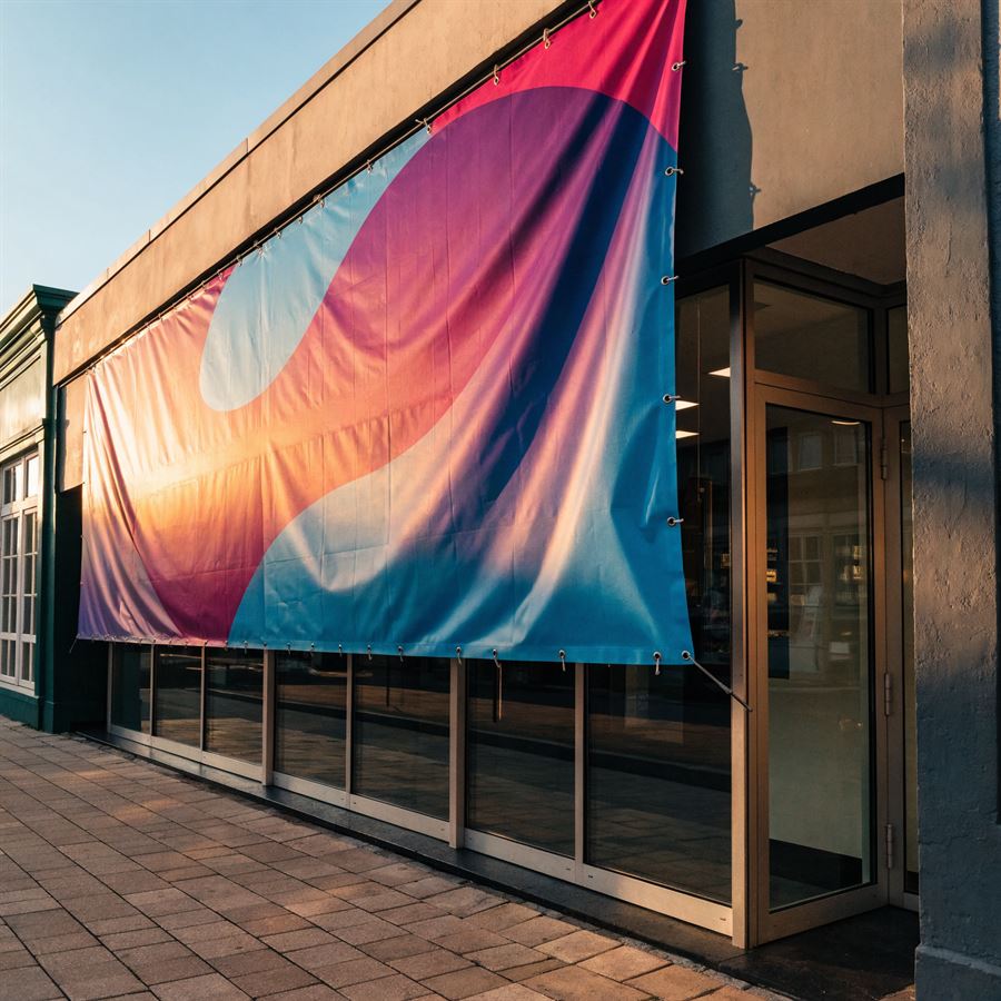 Banner em lona instalado na fachada de uma loja com ilhós e cabos