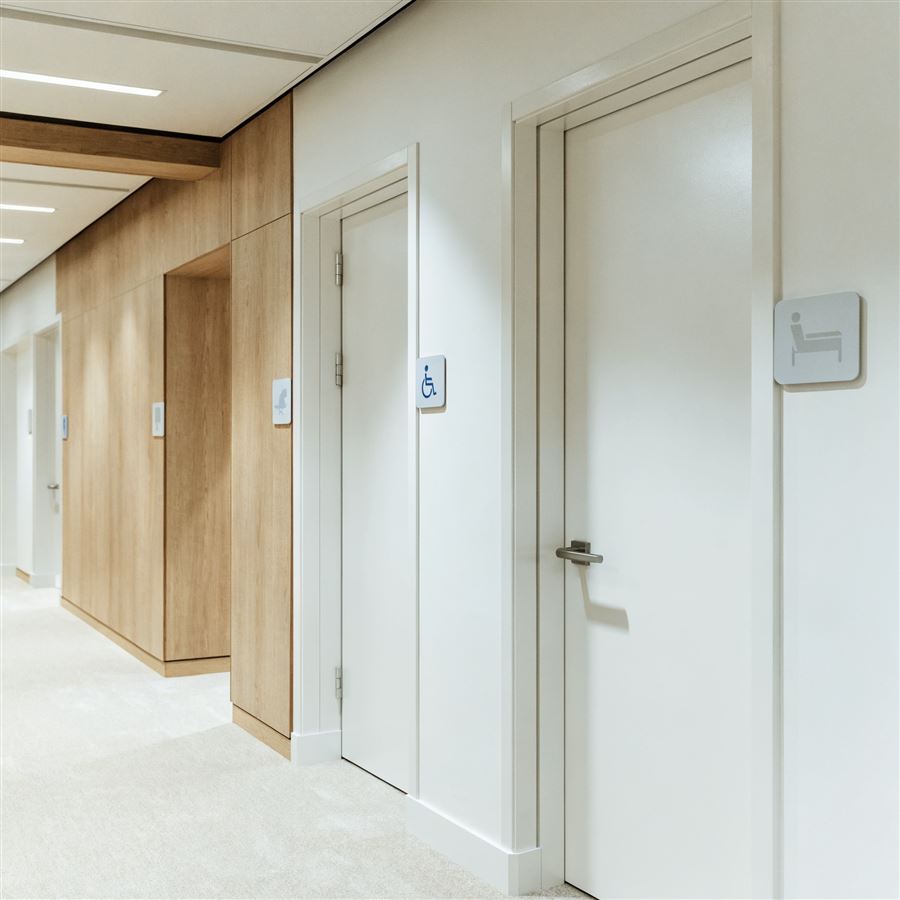 Corredor de clínica com placas de identificação de sala e acessibilidade