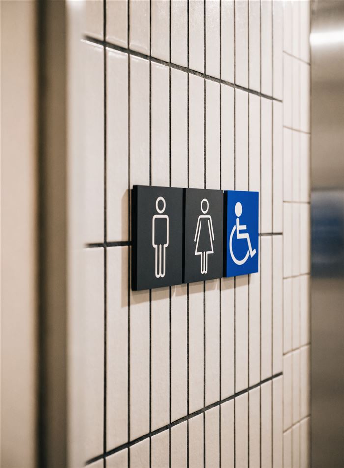 Placas de banheiro masculino, feminino e de acessibilidade em parede de azulejo