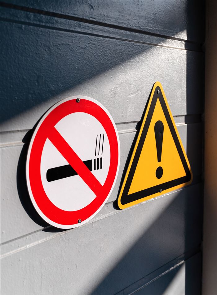 Placa redonda de proibido fumar e placa triangular de alerta instaladas em parede